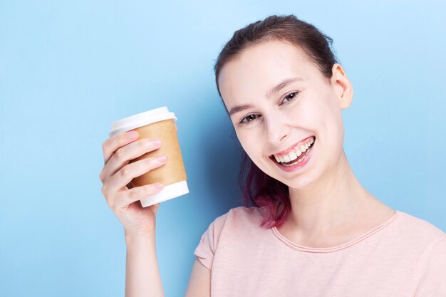 Young woman holds coffee paper cup and smiles