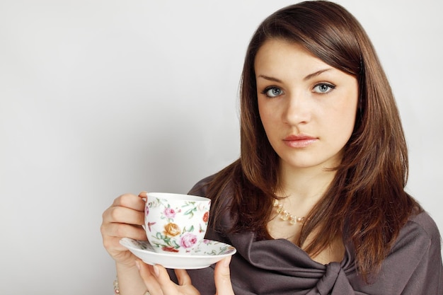 Young woman holds cup with the beverage