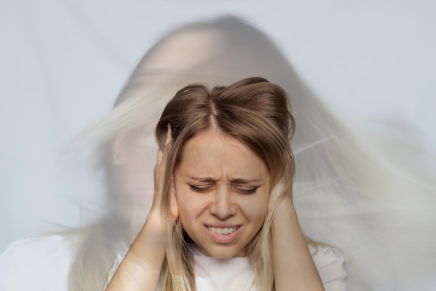 Young woman holds her head and covers her ears with her hands Schizophrenia split personality