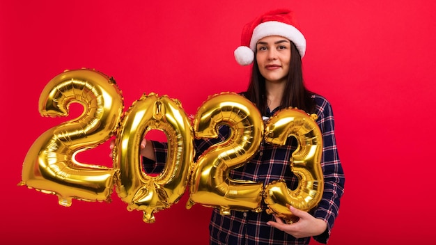 A young woman holds the numbers 2023 from balloons The coming New Year