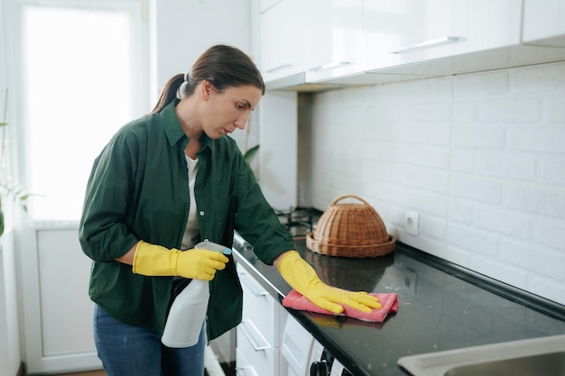 Young Woman at Home Cleaning Kitchen Table with Gloves