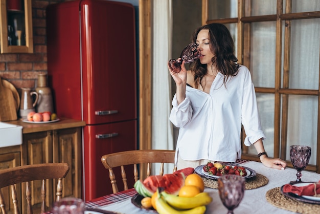 ガラスから水を飲む台所で家にいる若い女性。