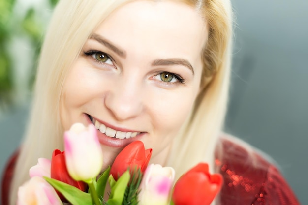 クローズアップ笑顔のチューリップの花束を保持している家の母の日のコンセプトで若い女性。