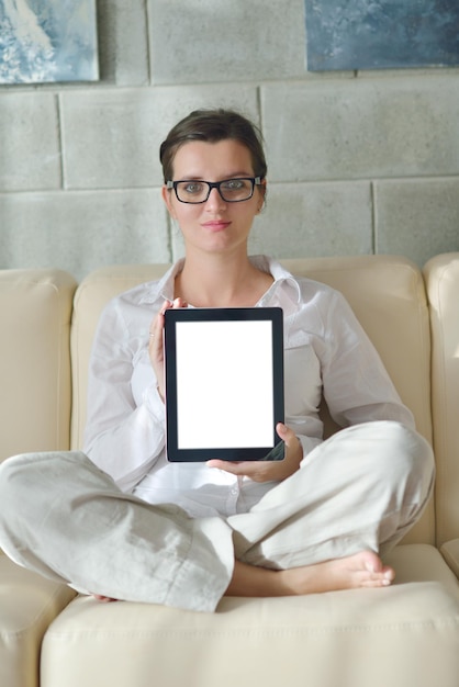 Young woman at home relaxing in her lliving room reading a digital tablet PC surf internet and work