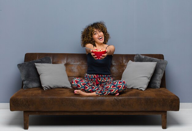 Young woman at home sitting on a sofa and having a breakfast