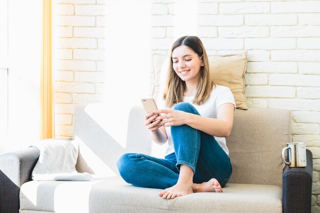 young woman at home on sofa speaking with friends on phone