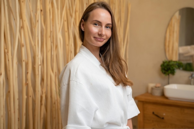 Giovane donna in una vestaglia in bagno guardando la telecamera