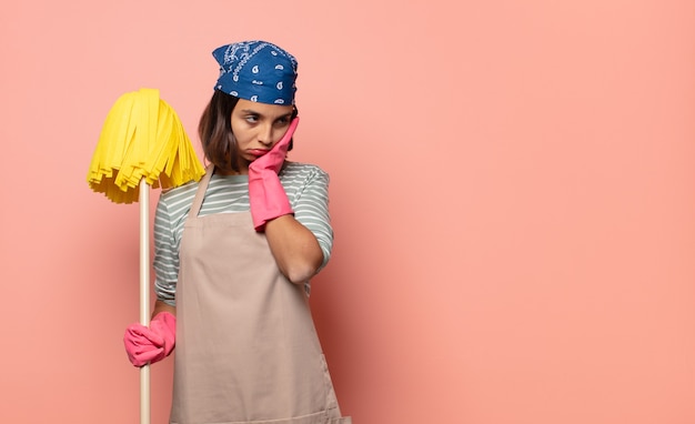 Young woman housekeeper feeling bored, frustrated and sleepy after a tiresome, dull and tedious task, holding face with hand