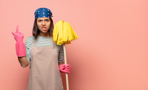 Young woman housekeeper feeling confused and puzzled, showing you are insane, crazy or out of your mind