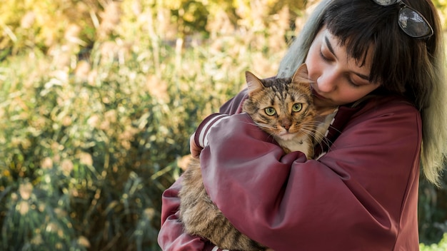 若い女性が庭で彼女のトラ猫を抱き締める