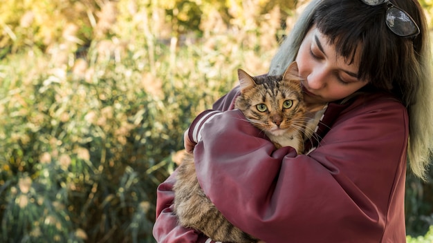 写真 若い女性が庭で彼女のトラ猫を抱き締める