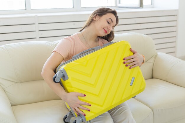  young woman hugging her yellow suitcase