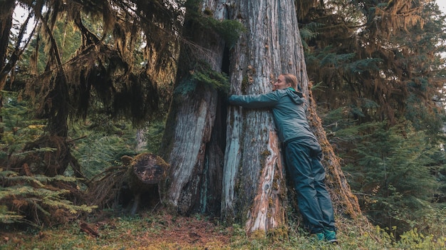 Foto giovane donna che abbraccia un albero sull'isola di vancouver