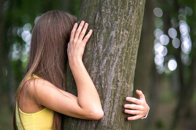 Молодая женщина, обнимая дерево