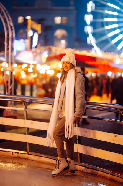 Young woman ice skating on a rink in a Festive Christmas fair in the evening Lights around