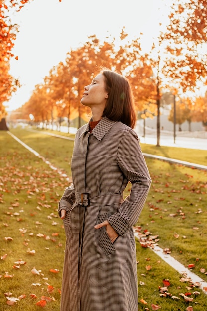 写真 コートを着た若い女性が公園で秋を楽しんでいます