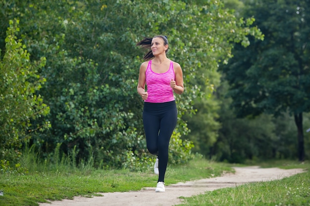 写真 スポーツユニフォームの若い女性が公園のトラックを走る