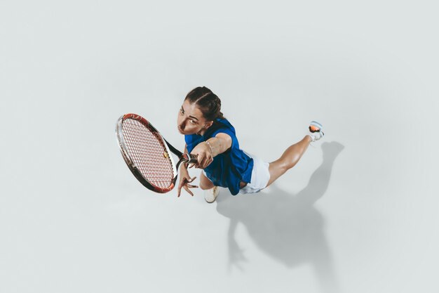 사진 테니스를 치는 파란색 셔츠를 입은 젊은 여자. 젊음, 유연성, 힘, 에너지.