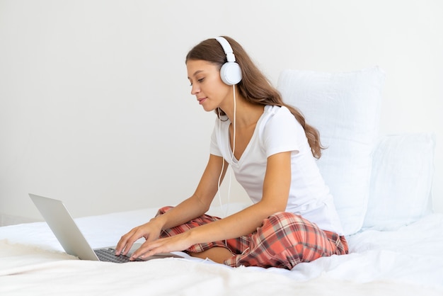 노트북을 사용하는 가정에서 일하는 온라인 공부 헤드폰에 젊은 여자