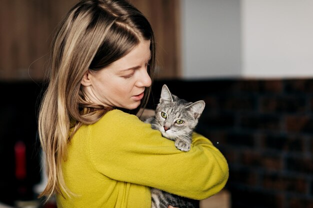 Фото Молодая женщина в домашней одежде обнимает свою кошку дома