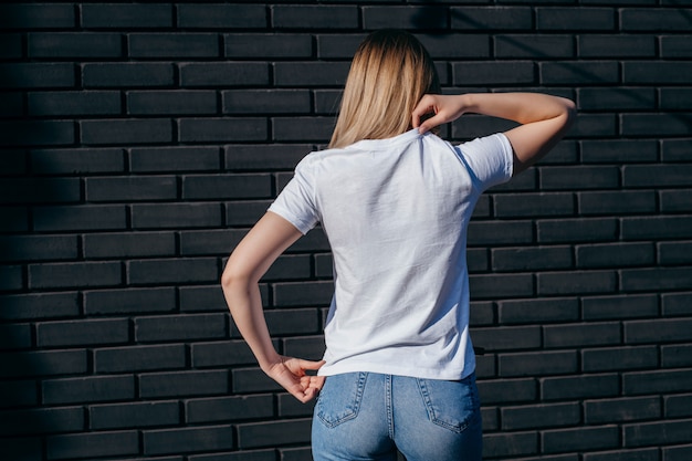 Фото Молодая женщина в рубашке и джинсах представляя outdoors