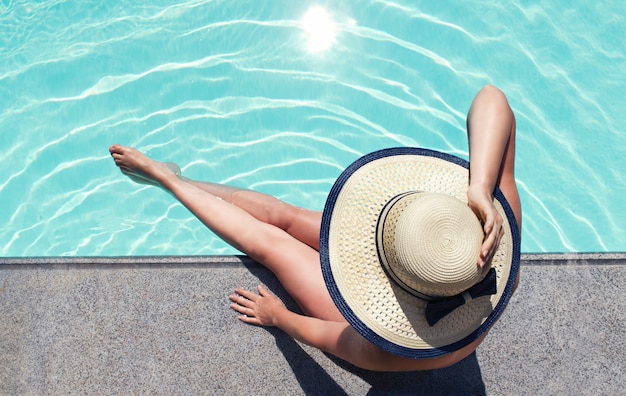사진 수영장 최고 전망으로 일광욕을 하는 모자를 쓴 젊은 여성.
