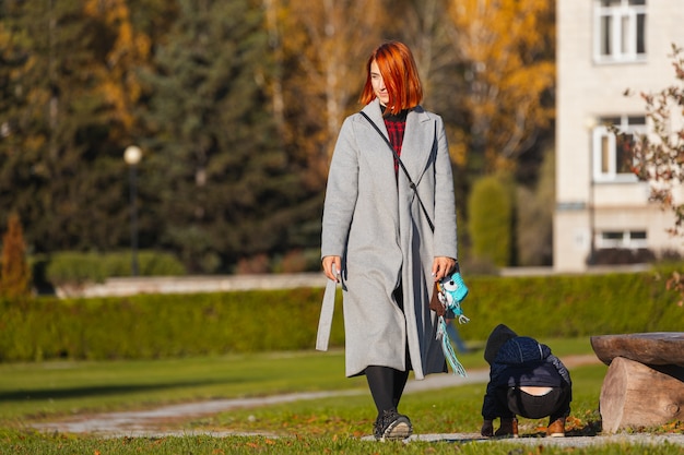 Фото Молодая женщина в теплой осенней одежде гуляет в городском парке