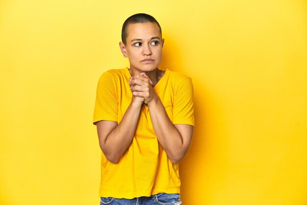 Фото Молодая женщина в желтой футболке на желтом фоне студии напугана и напугана