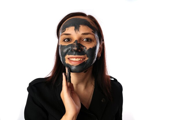 젊은 여성이 흰색 배경에 격리된 얼굴에 검은 마스크를 씌우고 건강한 생활 방식 뷰티 바디 케어의 개념