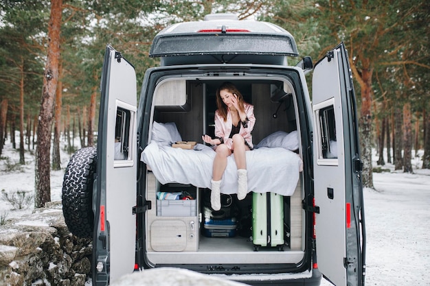 Young woman inside her campervan in winter relaxing and looking down