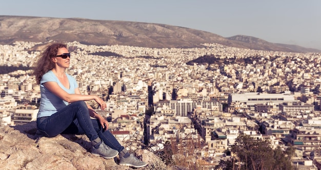 젊은 여자는 그리스 아테네의 도시 풍경을 배경으로