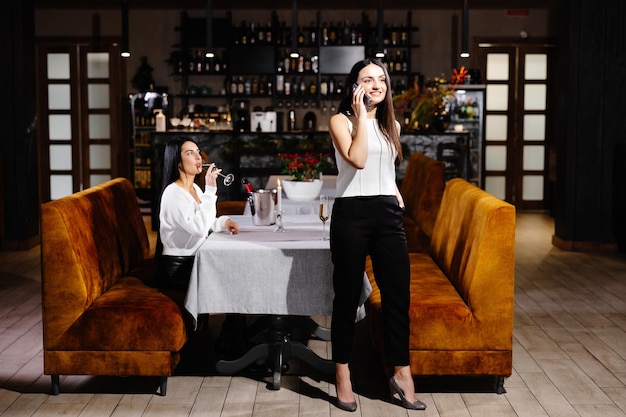 young woman is bored to date while her girlfriend having business cell on mobile phone