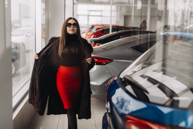 Молодая женщина выбирает новую машину в автомобильном магазине
