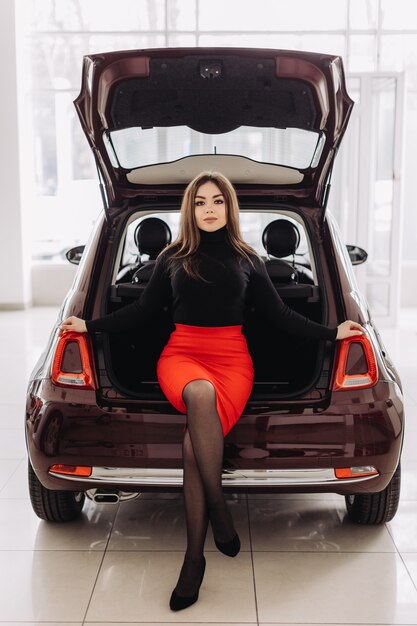 A young woman is choosing a new car in car store