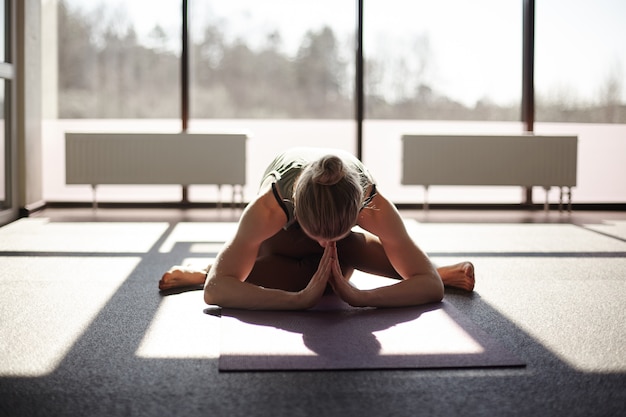 A young woman is doing yoga in the gym. a girl meditates against the background of panoramic windows in a modern yoga studio. the concept of a healthy lifestyle, place for text