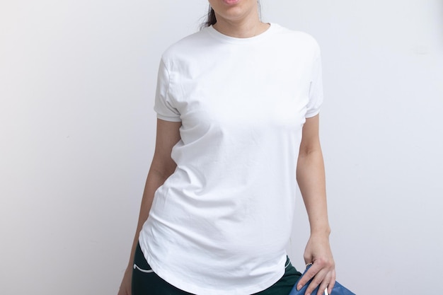 若い女性は、碑文の広告の描画のための空白の白いTシャツのモックアップに身を包んだ