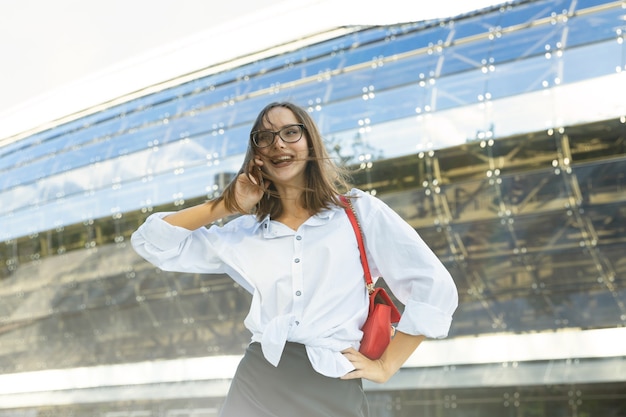 若い女性は電話で話しているビジネススタイルの服を着ています