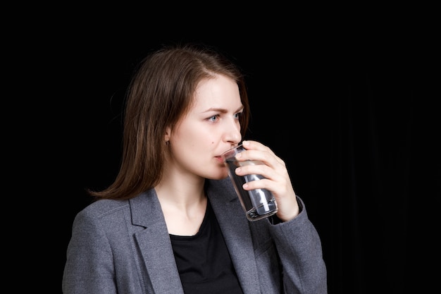 Young woman is drinking pure clean water from the glass