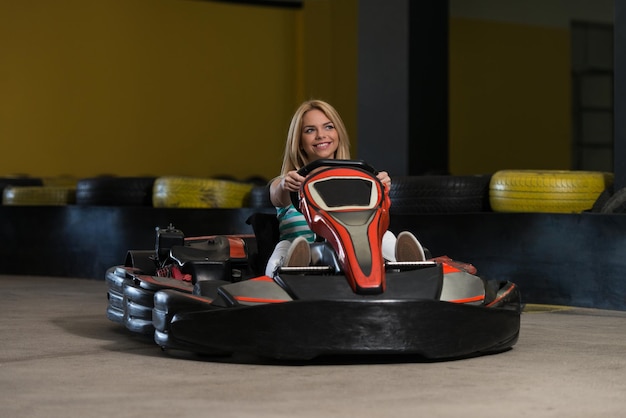 La giovane donna sta guidando l'auto di gokart con velocità in una pista da corsa del parco giochi go kart è un popolare sport motorio per il tempo libero
