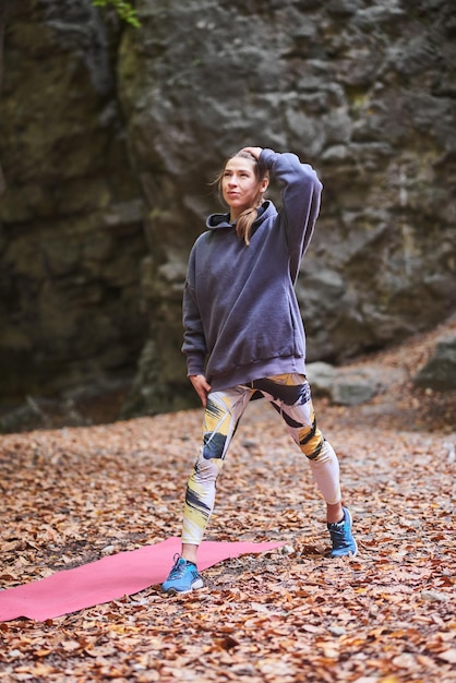 Young woman is engaged in fitness in the autumn park among the rocks The girl goes sports in nature