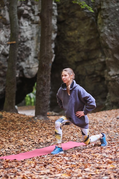 Young woman is engaged in fitness in the autumn park among the rocks The girl goes sports in nature