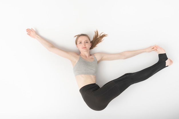 Photo young woman is engaged in gymnastics. development of flexibility. asanas in yoga. beautiful slender girl does hatha yoga on white background