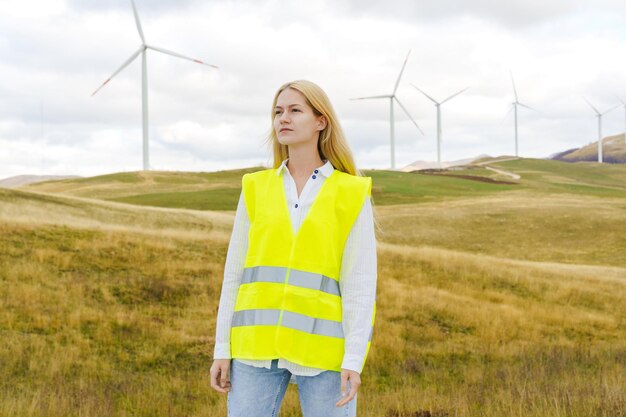 A young woman is an engineer of power systems against the background of wind turbines Green Economy