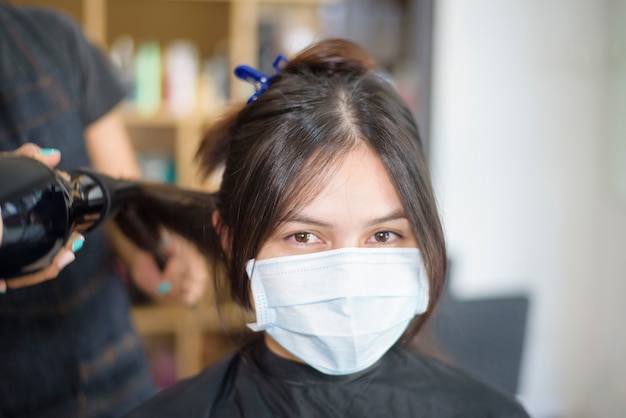 Premium Photo | A young woman is getting a haircut in a hair salon ,  wearing face mask for protection covid-19 , salon safety concept