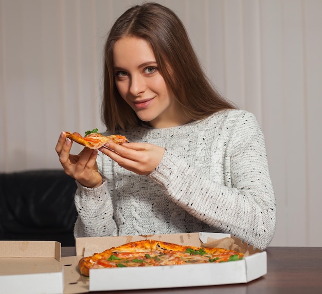 젊은 여자가 피자를 맛볼 것입니다