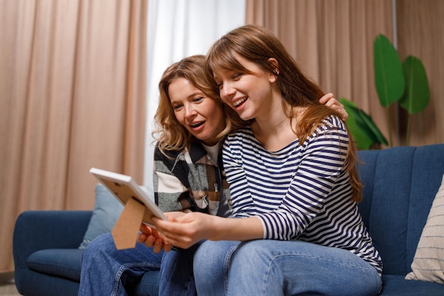 Young woman is having fun with her mother looking through old childhood photos