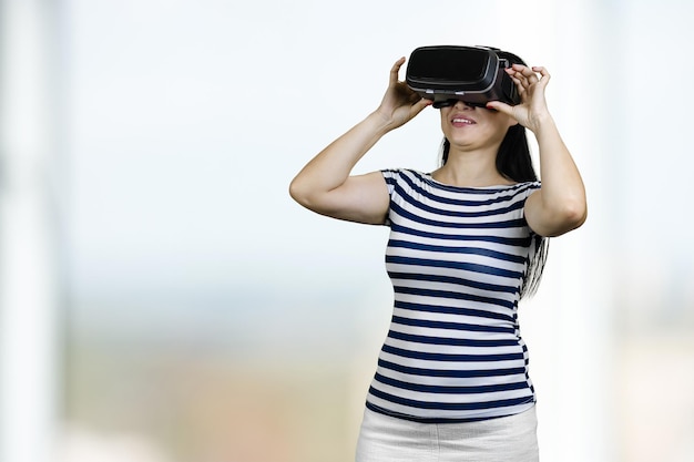 Young woman is having virtual reality experience bright blurred background