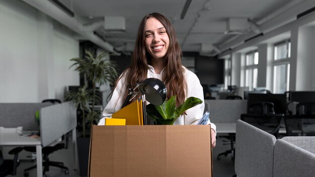 A young woman is holding a cardboard box with personal belongings New job in the office