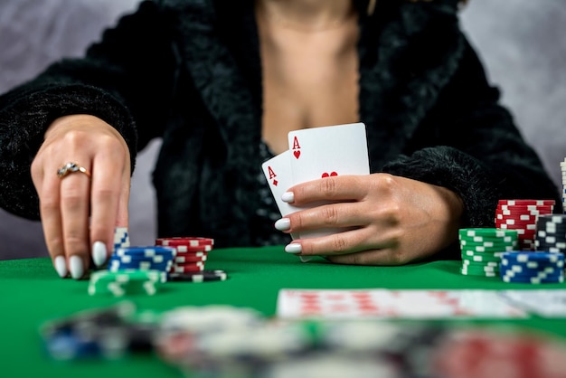 Молодая женщина держит игровые фишки и карты казино за столом в красивом платье