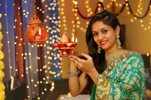 A young woman is holding lamp in hands and smiling